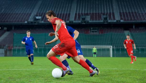 Football player challenging for ball on field during match.